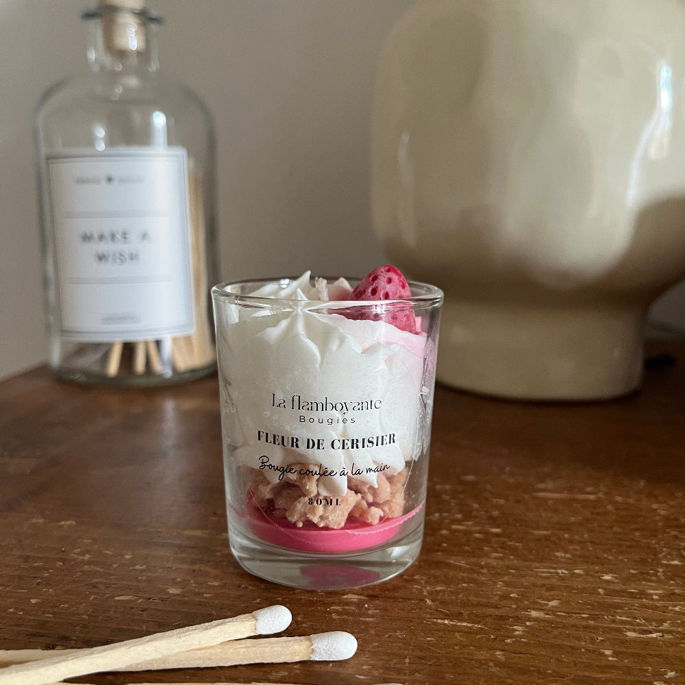 Petite bougie chantilly parfum fleur de cerisier avec une petite fraise en cire sur le dessus et de la chantilly en cire. 